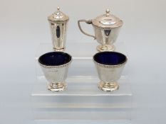 A George V Art Deco hallmarked silver four piece cruet set with blue glass liners,