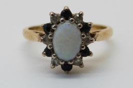 A 18ct gold ring set with an opal surrounded by diamonds and sapphires (size J)