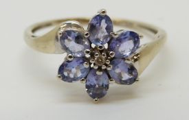 A 9ct white gold ring set with a diamond surrounded by tanzanite in a flower cluster (size M)