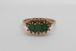 A 9ct gold ring set with three oval cut emeralds surrounded by diamonds (size N/O)