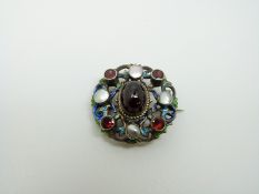 An Austro-Hungarian silver brooch set with a large garnet cabochon to the centre surrounded by blue