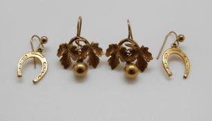 A pair of yellow metal horseshoe earrings and a pair of yellow metal earrings in the form of leaves,