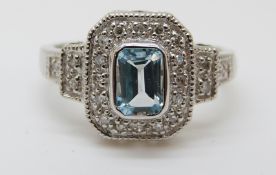 A 9ct gold ring set with a topaz surrounded by diamonds in a rectangular setting (size M)