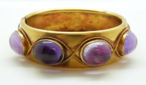 A late Victorian pinchbeck/ yellow metal hinged bangle set with eight large foiled amethyst