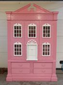 A pink painted child's wardrobe in the form of a doll's house,