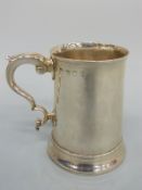 A Georgian hallmarked silver tankard of plain tapering form with C scroll handle,