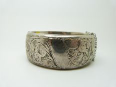 A hallmarked silver bangle with engraved foliate decoration