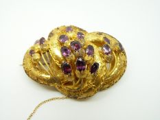 A Victorian yellow metal brooch of knotted design set with foiled oval cut almandine amethysts with