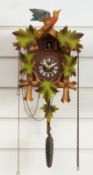 A mid to late 20thC cuckoo clock with painted vine leaf case decoration and pine comb weight