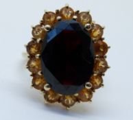 A 9ct gold ring set with a garnet surrounded by quartz (size J)