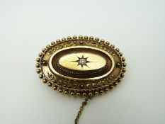 A Victorian 15ct gold brooch set with an old cut diamond in a star setting and foliate border,
