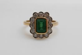 An 18ct gold ring set with an emerald cut emerald of approximately 1ct surround by diamonds (size