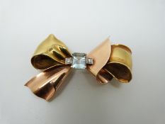 A 14k bi-coloured gold bow brooch set with an emerald cut aquamarine measuring approx 2.