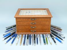 A pen collector's cabinet with four fitted drawers containing a collection of pens including