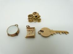 Four 9ct gold charms, key, drum, gate and a coronation coach, 7.
