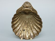 A hallmarked silver shell shaped dish raised on three ball feet,