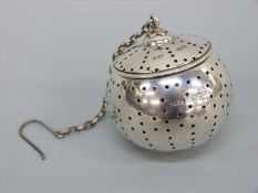 An Edward VII hallmarked silver 'drop in' tea strainer with hinged lid and suspension chain,