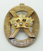 A Victorian pendant/brooch with engraved foliate decoration featuring a cross and a crown set with