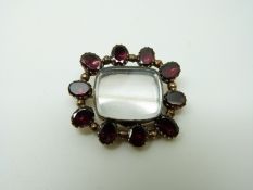 A Victorian brooch set with foiled garnets with glass compartment to the centre