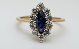An yellow metal ring set with a marquise cut sapphire surrounded by diamonds (size L)