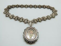 A Victorian silver locket decorated with applied floral and foliate gold decoration on a Victorian