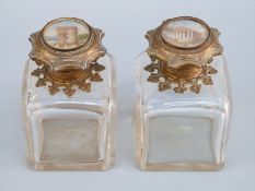 A pair of French scent bottles with ornate hinged tops inset with hand decorated Roman buildings,