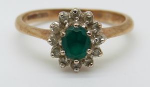 A 9ct gold ring set with an apple green oval emerald surrounded by diamonds (size K)