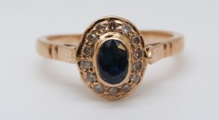A yellow metal ring set with an oval sapphire surrounded by diamonds (size M)