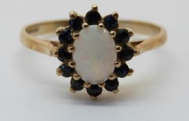 A 9ct white gold ring set with an opal surrounded by sapphires (size Q)