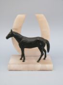 A spelter horse figure on an alabaster horseshoe base, H14.