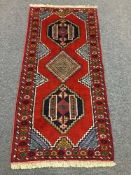A fringed Persian rug on red ground,
