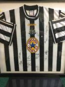 A framed and signed Newcastle United Football shirt - signed by the team bearing Newcastle Brown