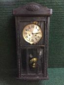 An oak cased wall clock with pendulum and key