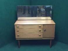 A mid 20th century teak dressing chest fitted a cupboard and three drawers