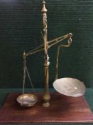A set of antique brass balance scales mounted on mahogany plinth