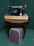 A walnut pie crust edge coffee table together with a Singer sewing machine in case