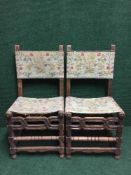 A pair of carved oak dining chairs upholstered in floral tapestry
