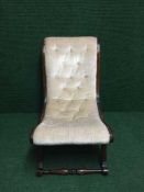 A mahogany nursing chair upholstered in beige button fabric