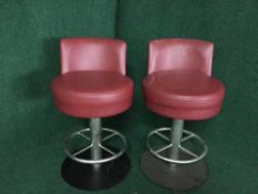 A set of four red leather swivel bar stools on metal bases