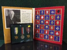 A framed set of three WW II medals together with a volume of the Great British Regiments