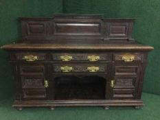 A late 19th century heavily carved oak sideboard with brass drop handles
