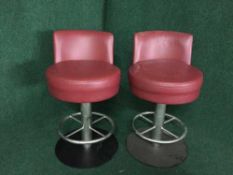 A set of four red leather swivel bar stools on metal bases