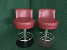 A set of four red leather swivel bar stools on metal bases