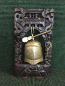 A oriental brass gong and beater on a carved hardwood stand