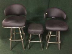 Two black leather bar chairs on chrome bases and a matching bar stool