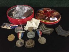 A tin of assorted coins, rank badges,