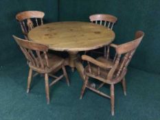 A circular pine pedestal table and four dining chairs