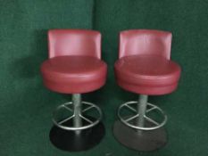 A set of four red leather swivel bar stools on metal bases