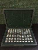 A boxed set of 100 silver tokens depicting cars through the ages