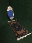 A small fringed Turkish silk prayer mat and a wall mirror